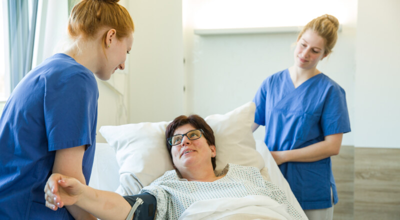 Azubis messen Blutdruck an Patientin