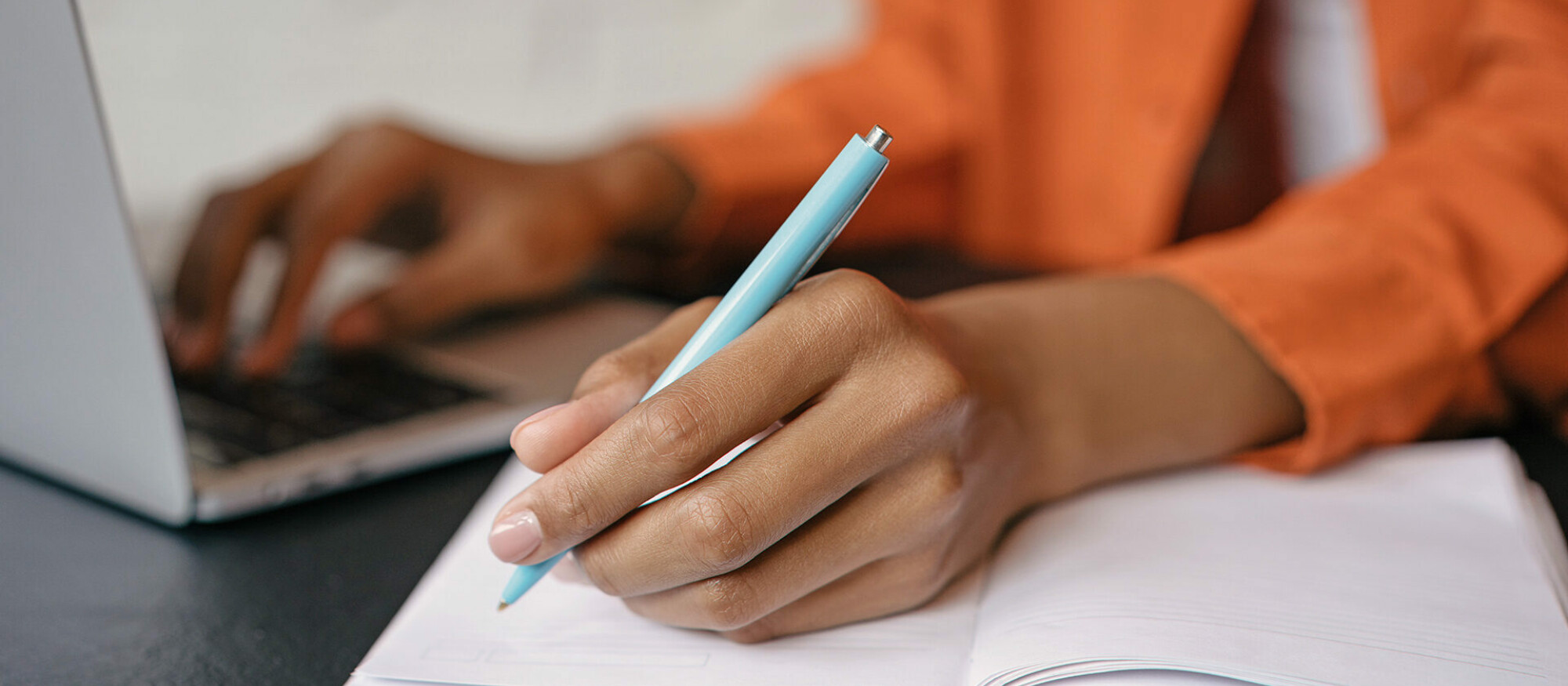 Frau mit Stift, Notizbuch und Laptop