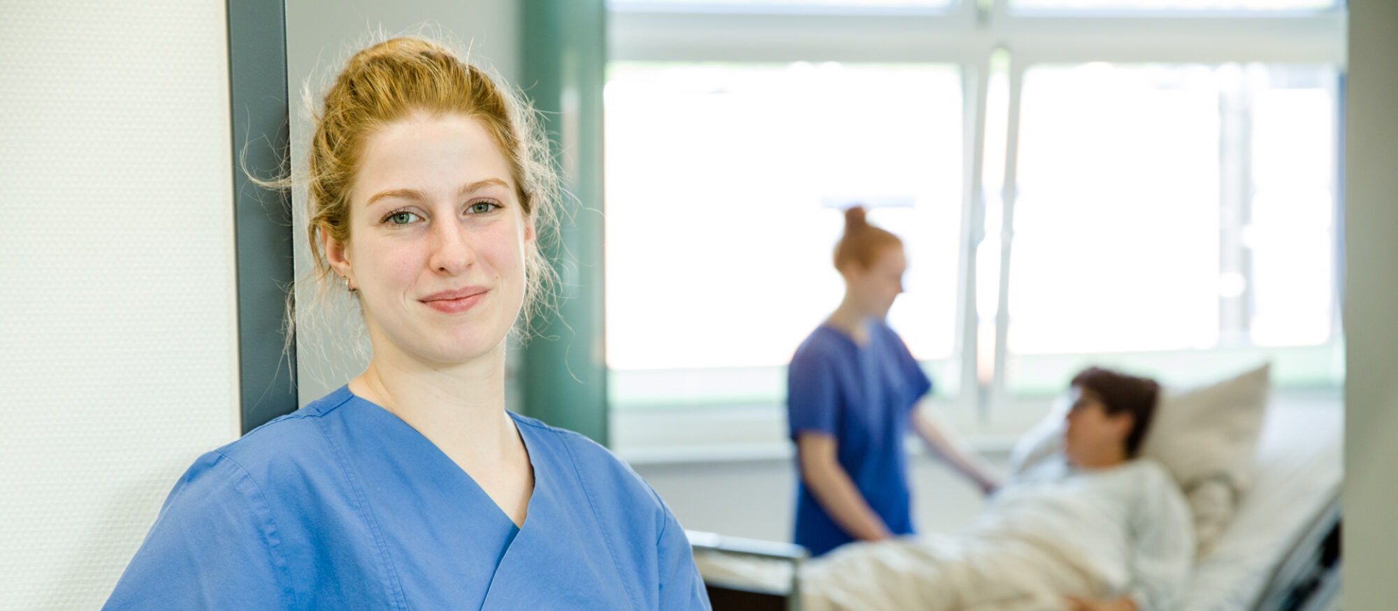 Pflegefachfrau-Auszubildende im Türrahmen vom Patientenzimmer