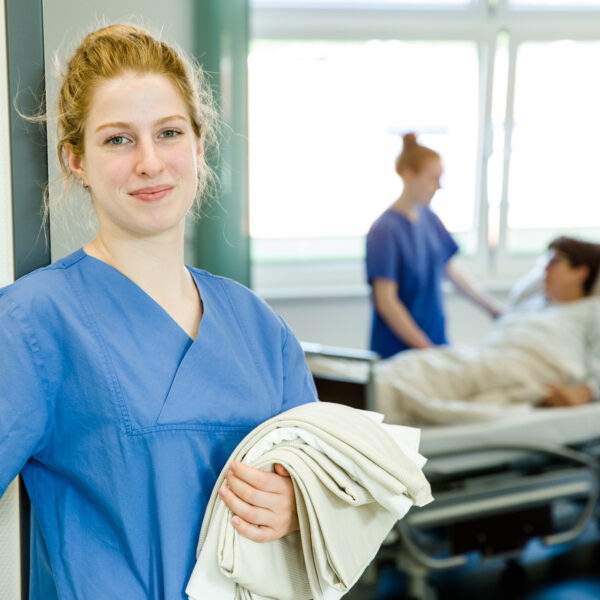 Pflegefachfrau-Auszubildende im Türrahmen vom Patientenzimmer